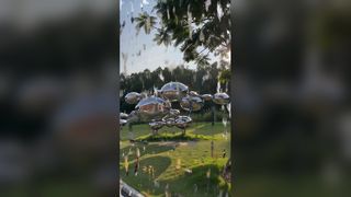 यह प्रतिबिंबित स्टेनलेस स्टील की मूर्ति अलग-अलग आकार के चिकने, गोल गोले से बनी है